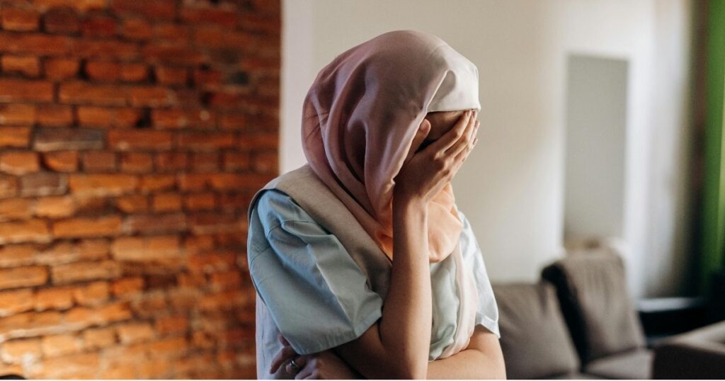 A South Asian woman hiding her facce representing cultural shame